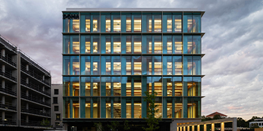 Office building lit from the inside against cloudy sky